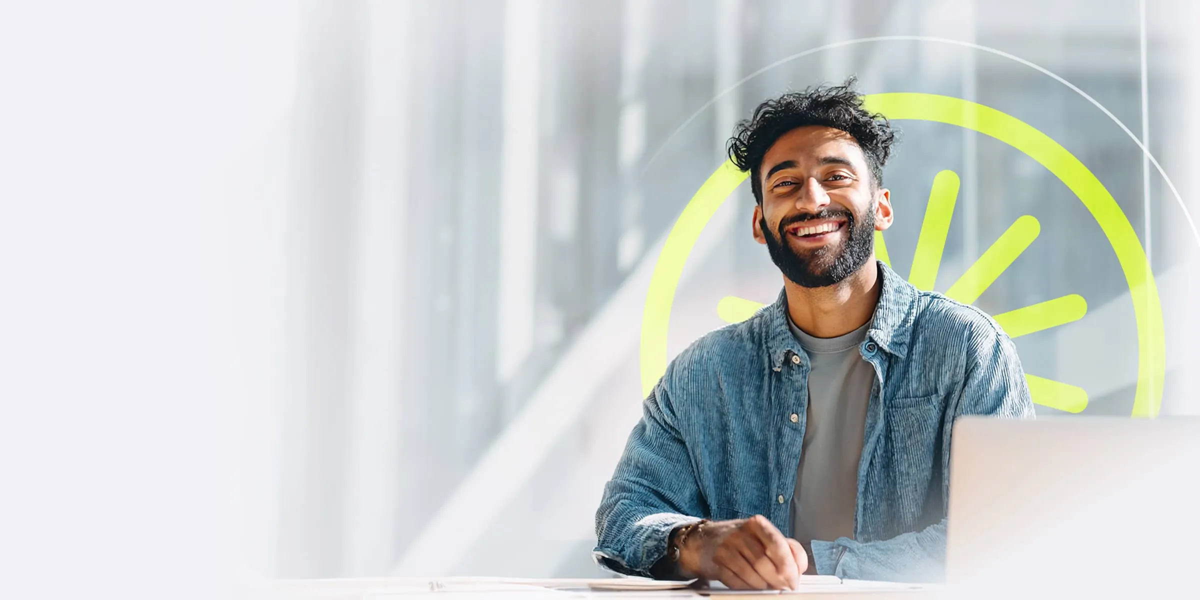 smiling man with a beard, sat in front of a laptop