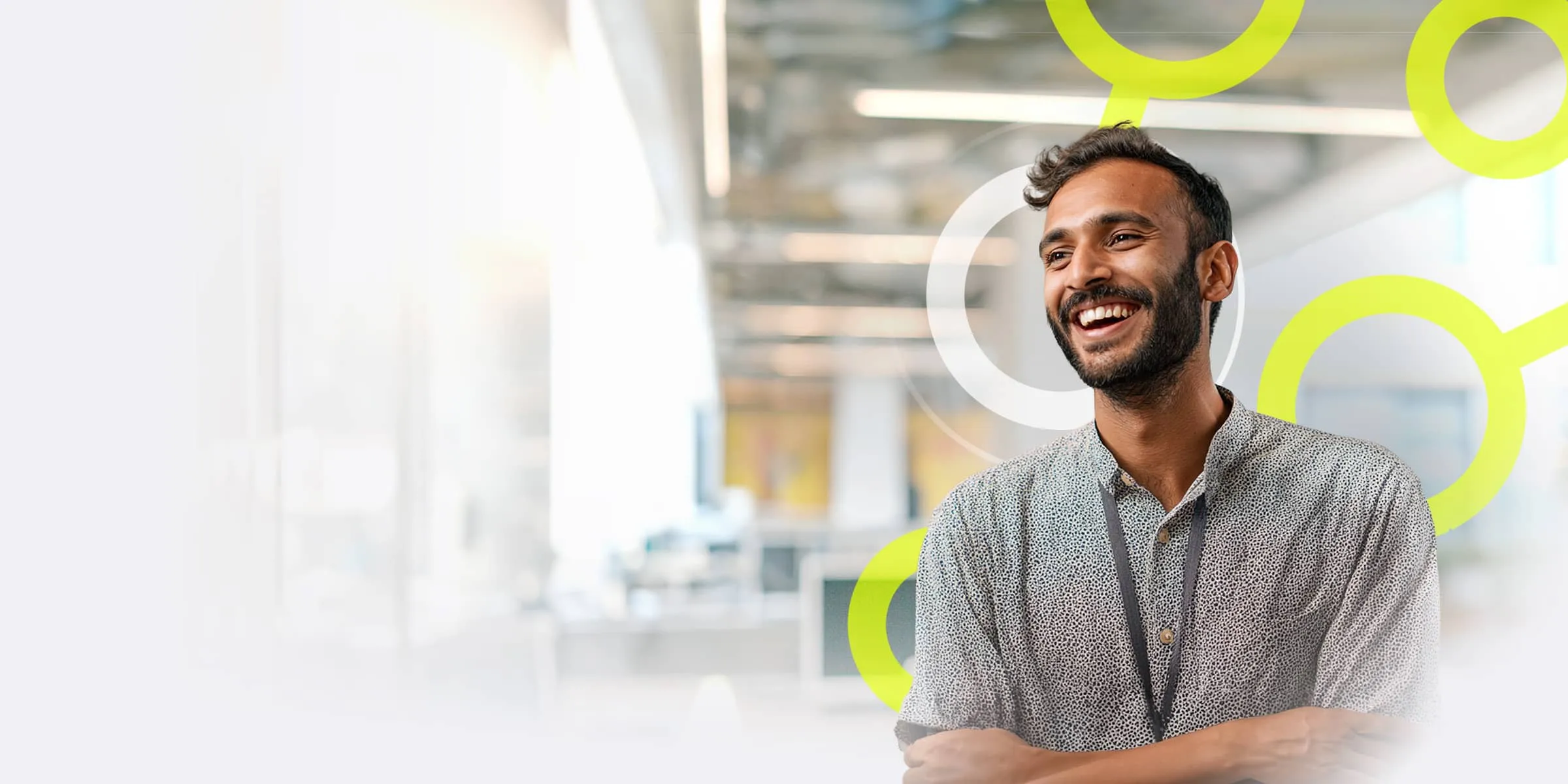 man with a beard is stood smiling in a bright modern office