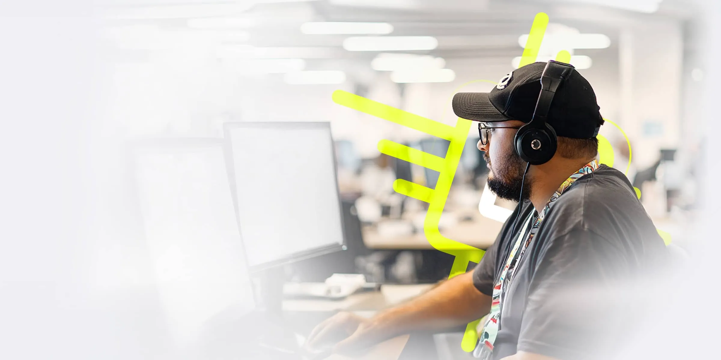A male programmer wearing glasses and a baseball cap stares at a screen full of computer code