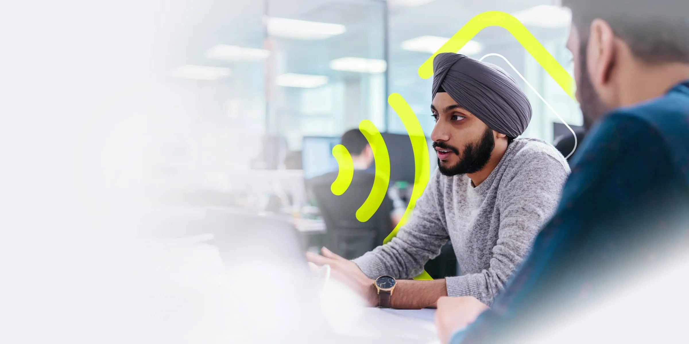 A Sikh male programmer wearing a turban discusses work with a colleague