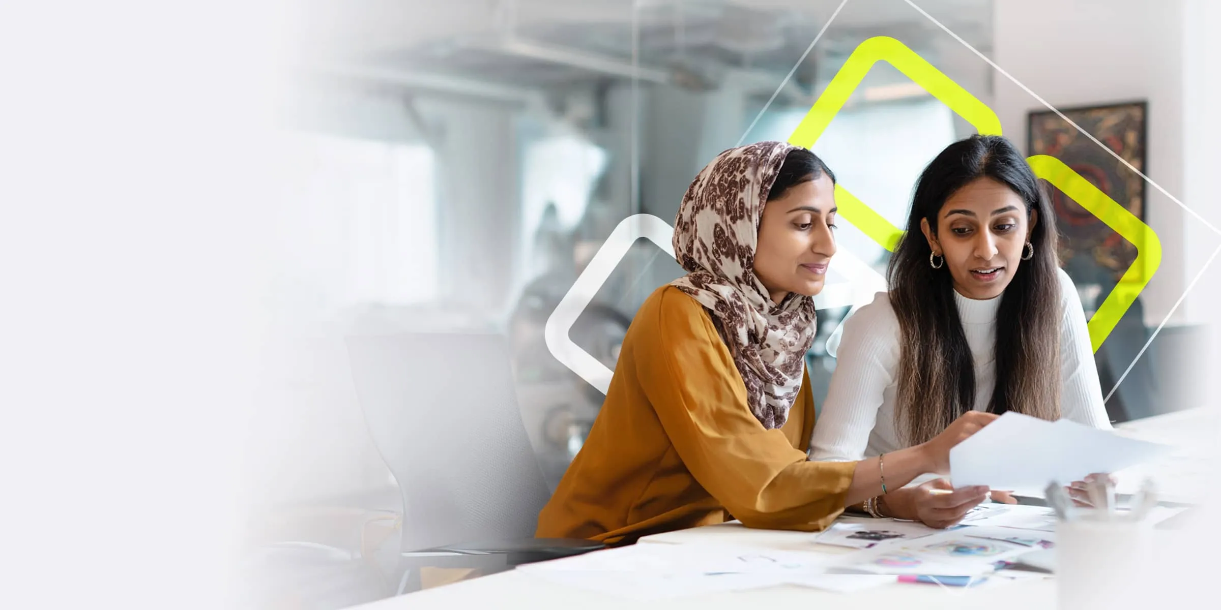 two smartly dressed women discuss work whilst looking at papers together