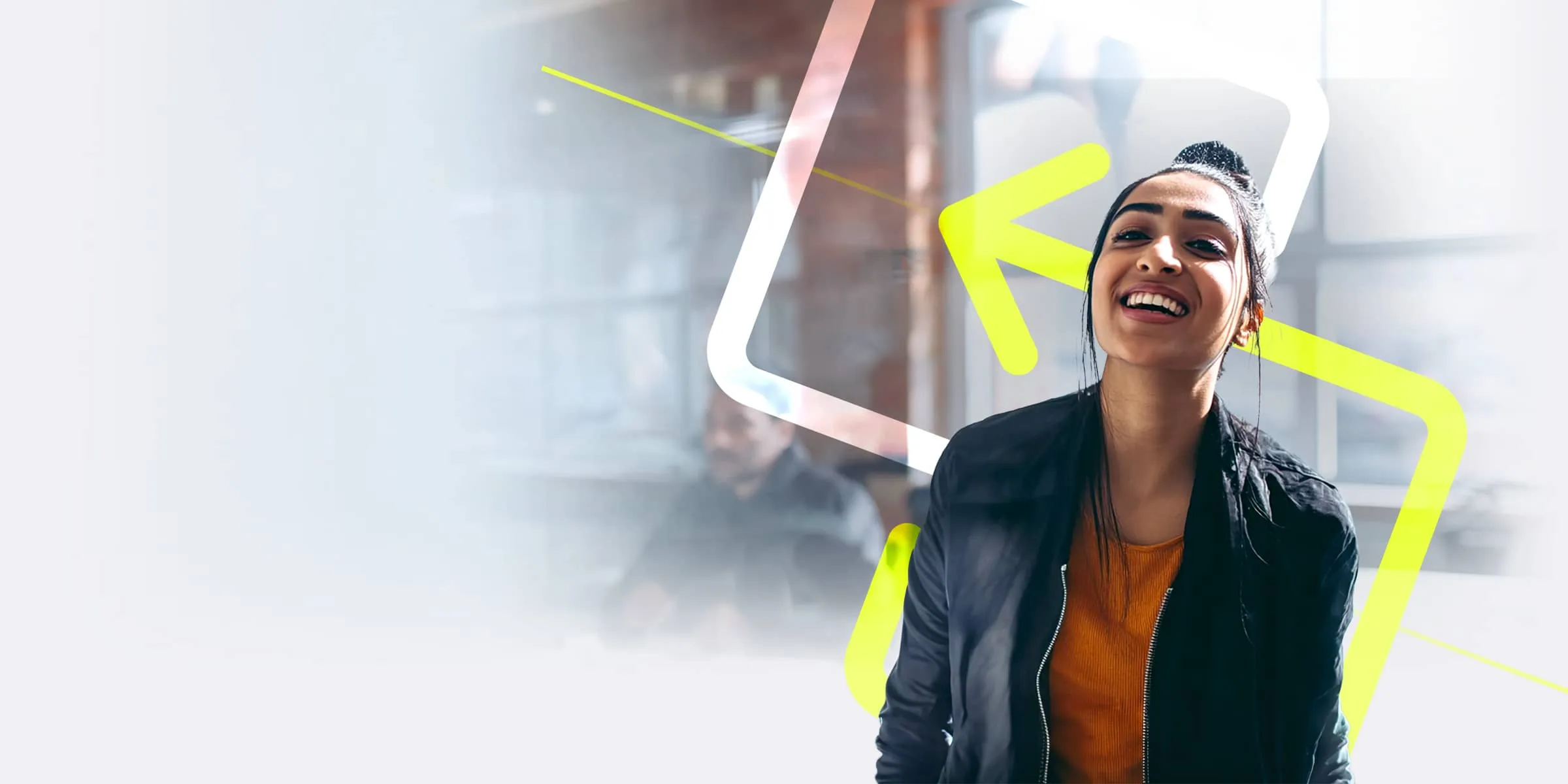 a young woman with hair tied into a bun, wearing a casual black jacket and orange top, smiles whilst looking into the camera